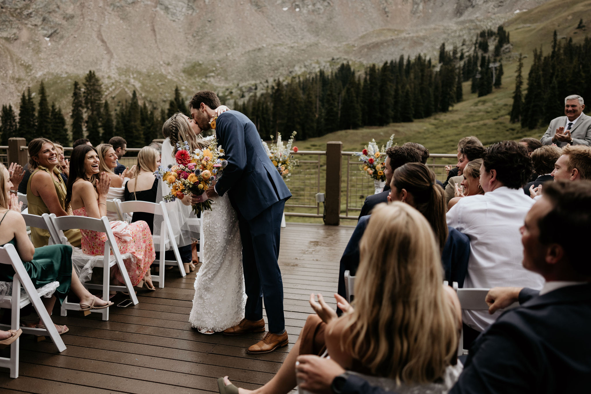 bride and groom kiss in the aisle during ski mountain wedding in colorado.
