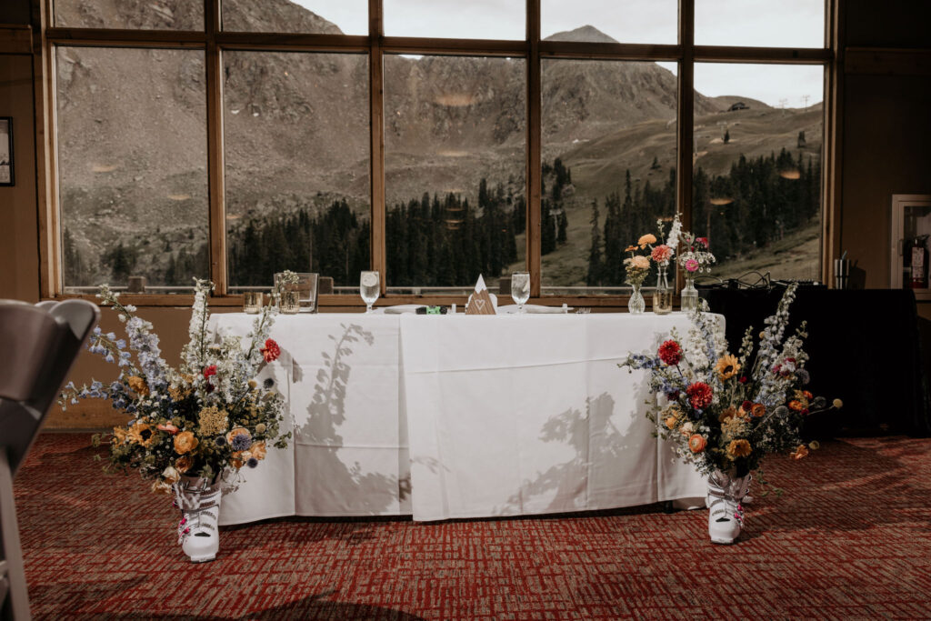 head table set up in front of mountain view window during a ski wedding at black mountain lodge.