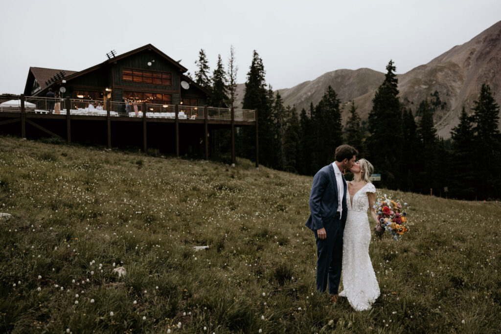 bride and groom kiss in front of colorado wedding venue, black mountain lodge at arapahoe basin.