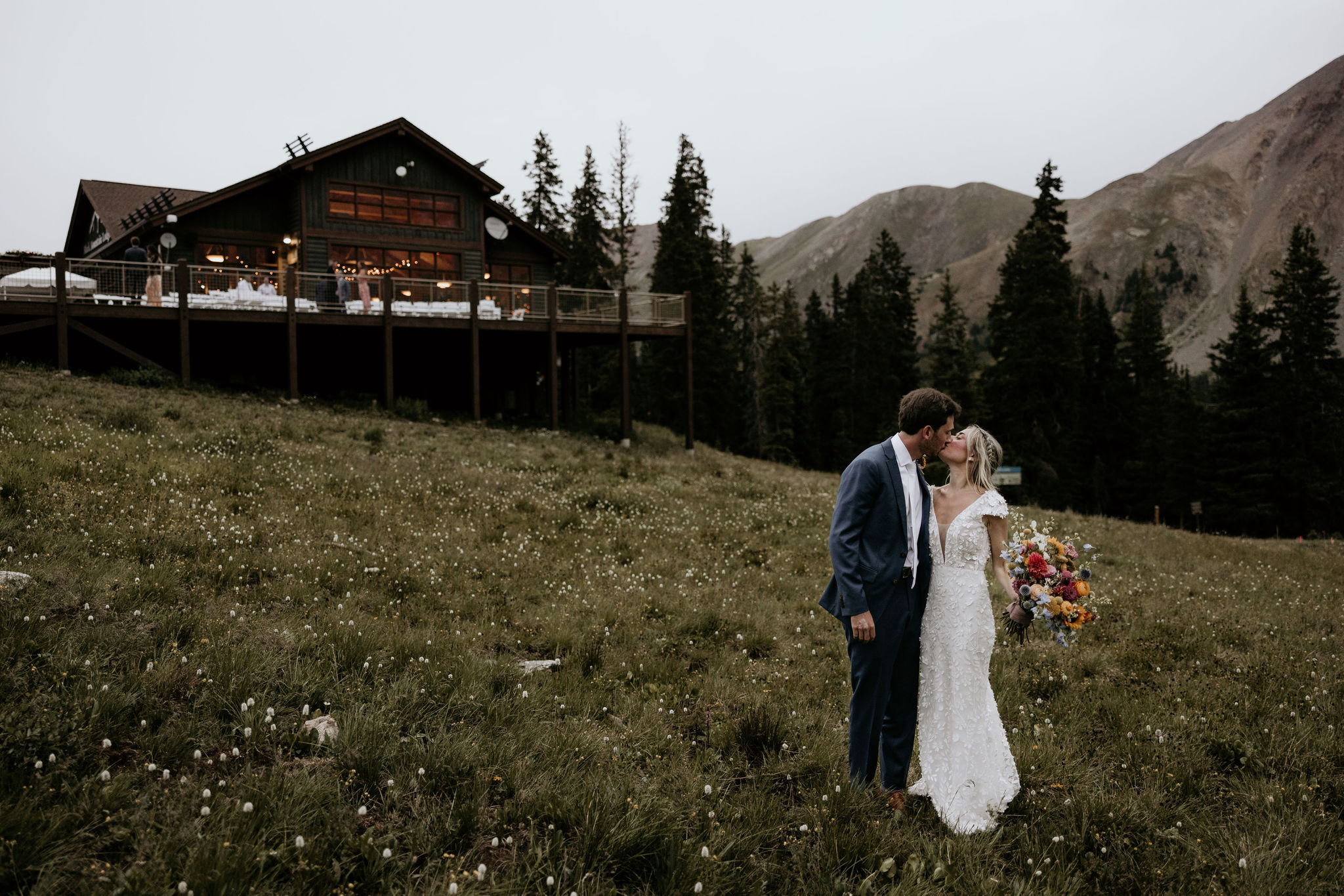 bride and groom kiss in front of colorado wedding venue at arapahoe basin.