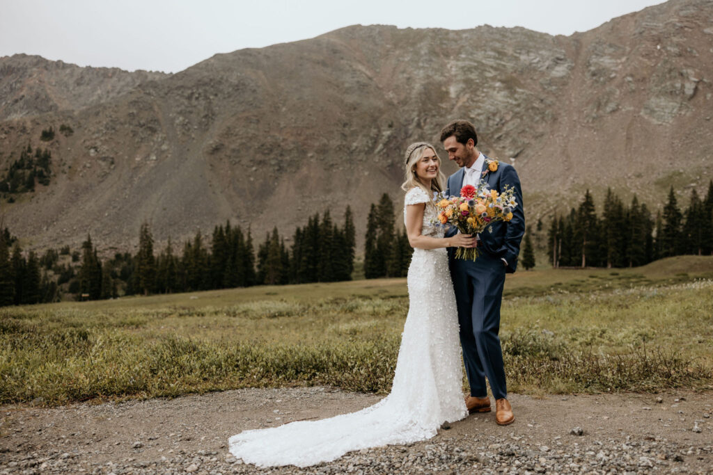 bride and groom smile and embrace during their ski mountain wedding in colorado.