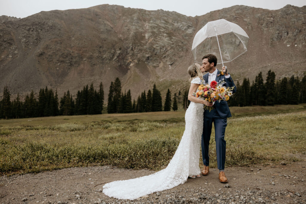 bride and groom kiss with mountainside in the background during their ski wedding in colorado.