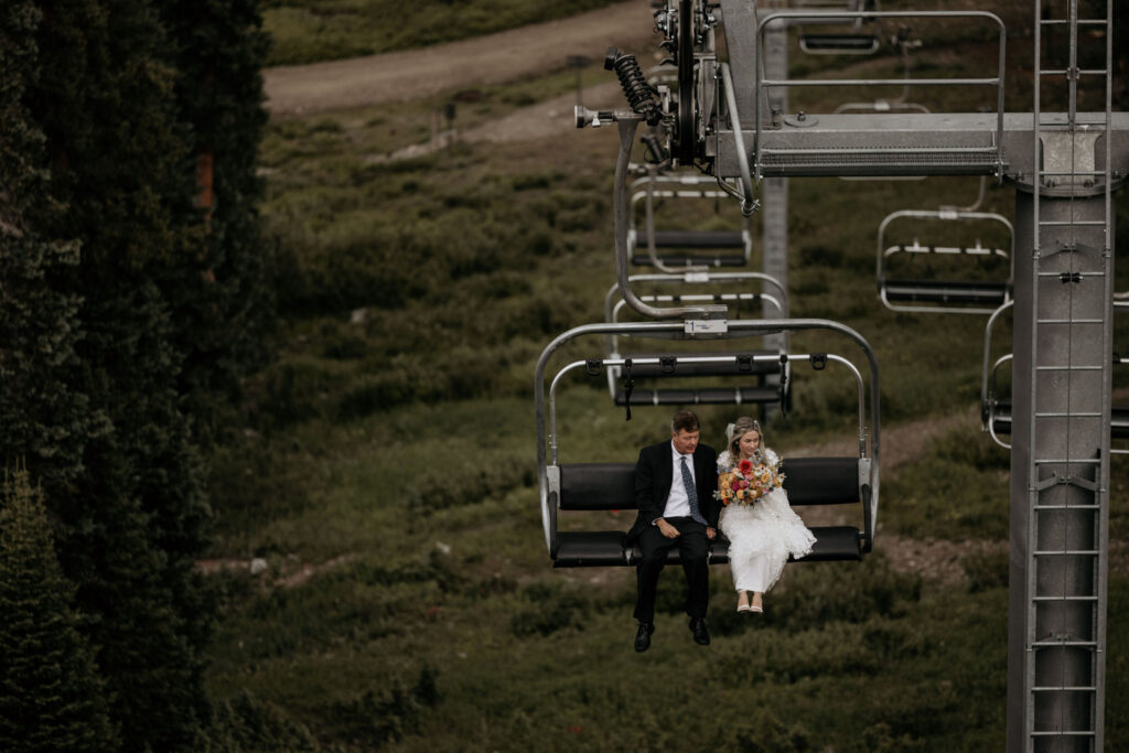 bride and father ride up ski lift for colorado mountain wedding ceremony.