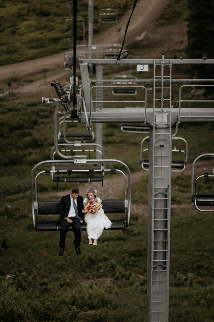 bride rides up ski lift with father on her way to colorado mountain wedding ceremony.