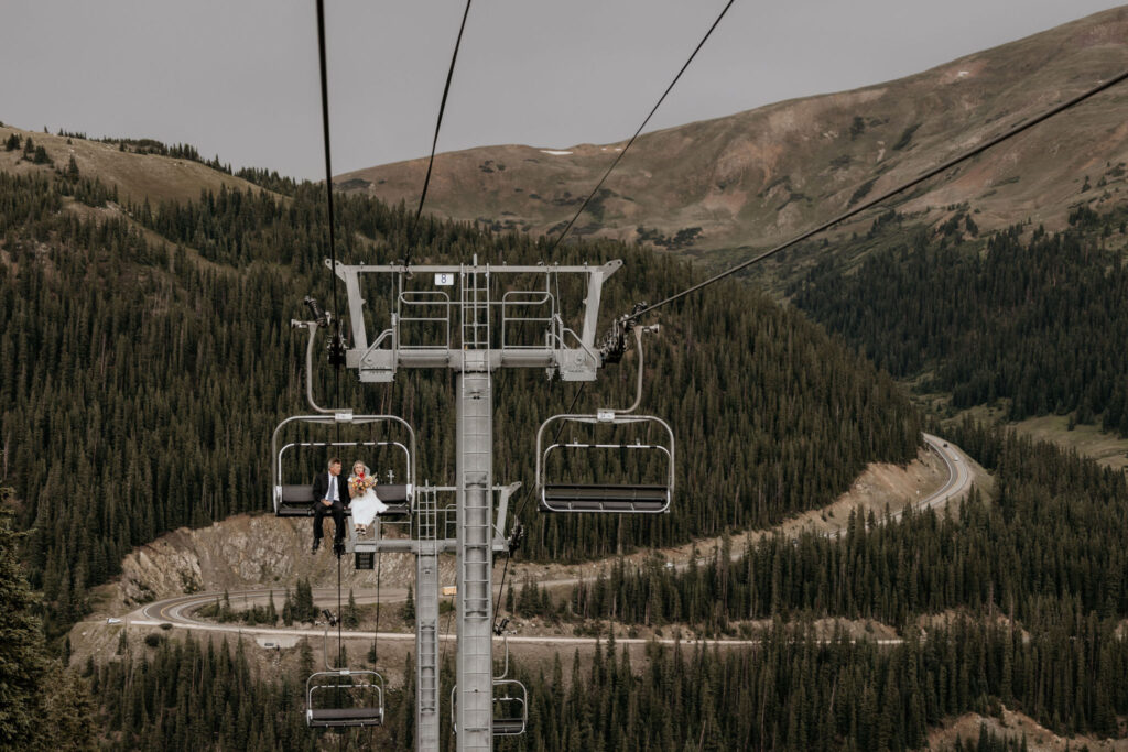 Bride and father ride up ski lift to her colorado mountain wedding.