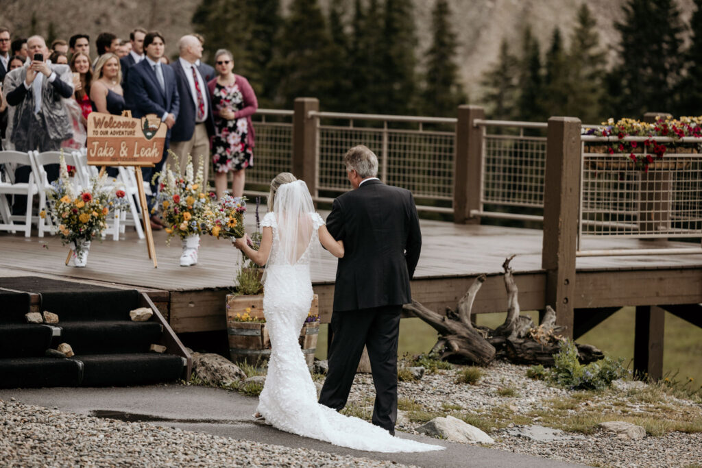 bride and father approach the ceremony space for her ski mountain wedding in colorado.