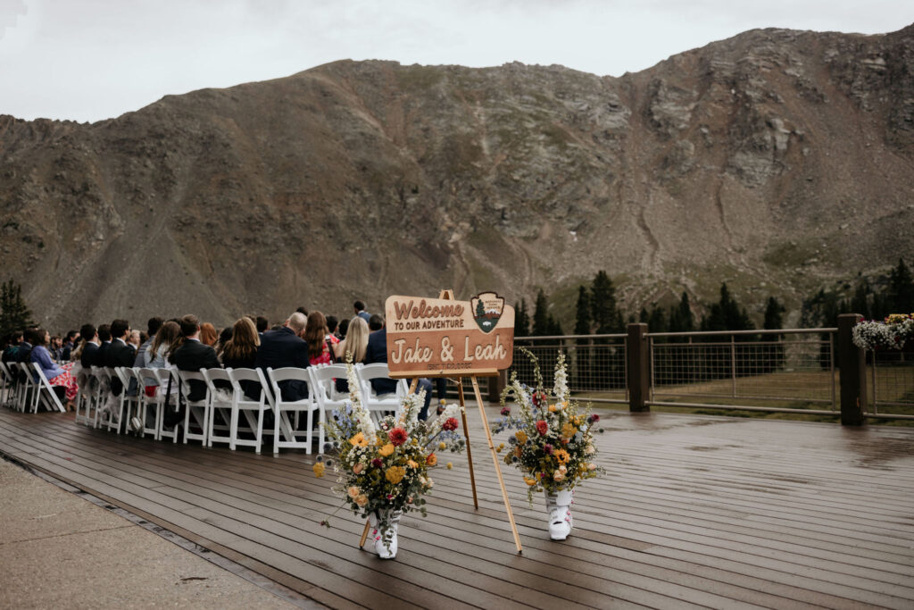 wedding sign with guests behind, views of the mountains, during colorado micro wedding.