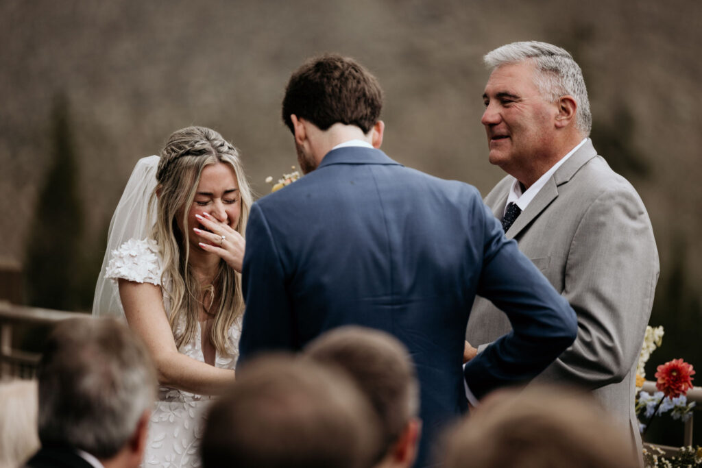 bride laughs during outdoor mountain wedding ceremony at black mountain lodge in colorado.