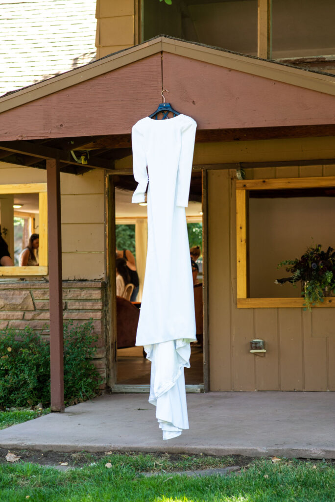 dress hangs on getting ready area at river bend during colorado micro wedding.