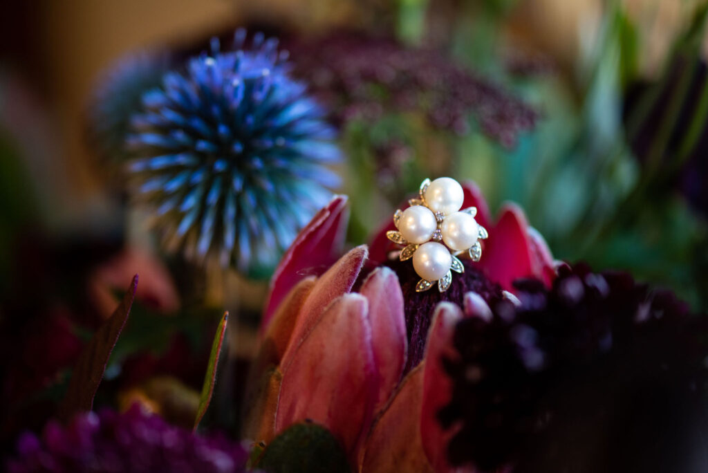 vibrant wedding arrangement by Plume and Furrow has a pearl ring on it, during a colorado micro wedding at river bend.