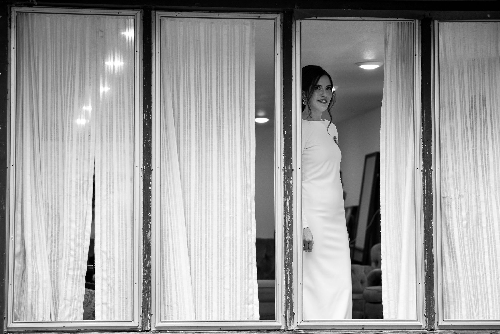 bride stands in the windows of the cottage at river bend for her colorado micro wedding.