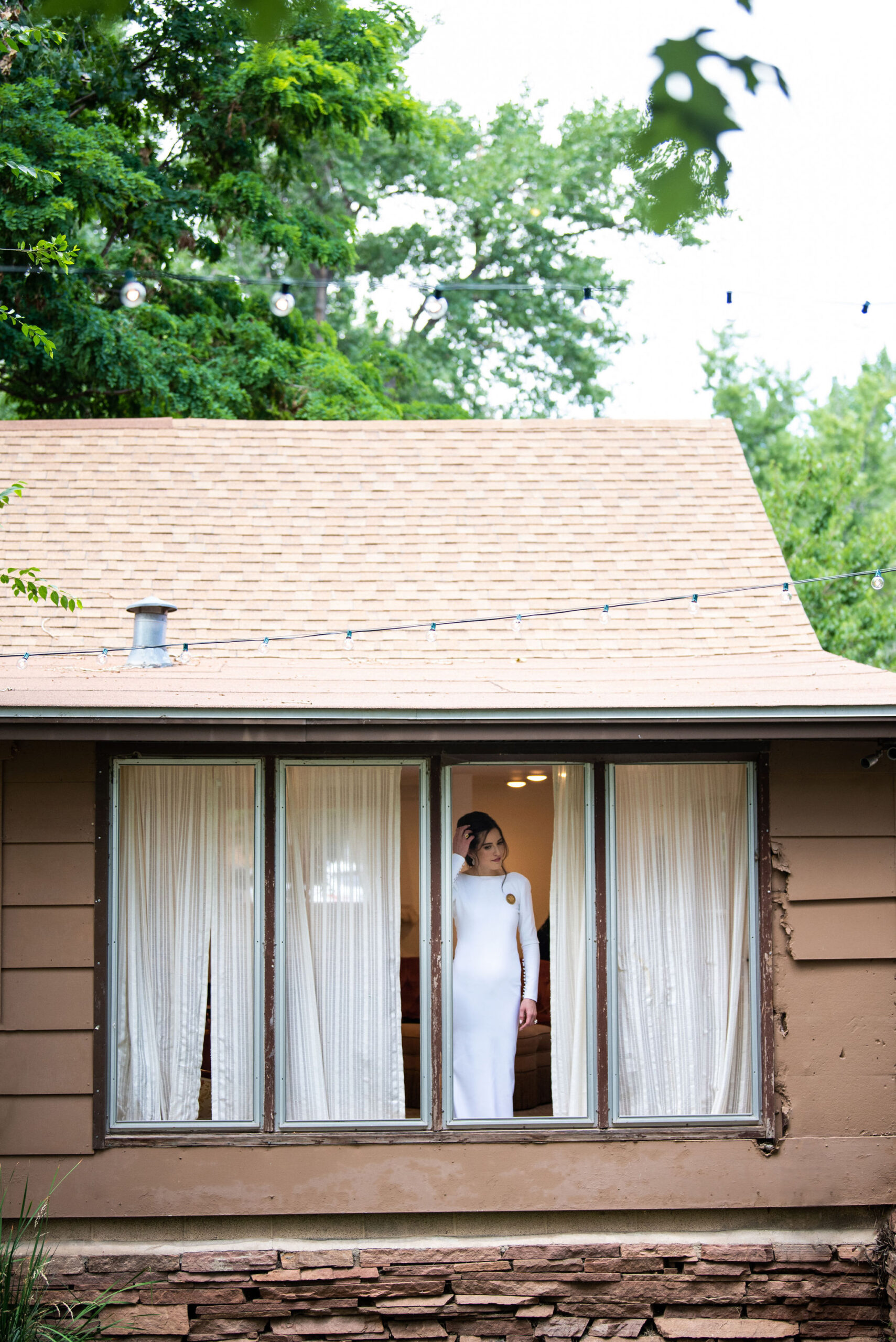 bride stands in window at river bend venue during colorado micro wedding.