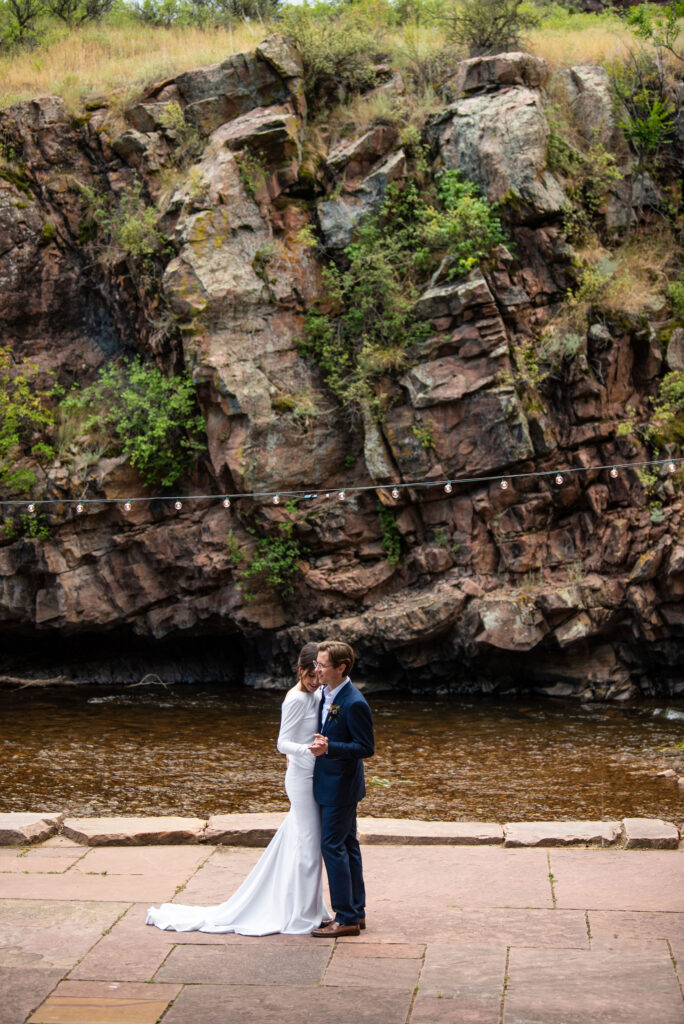 bride and groom dance by the river during their micro wedding in lyons colorado at river bend venue.
