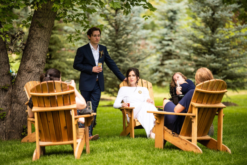 bride and groom sit with guests outside at colorado micro wedding at river bend.