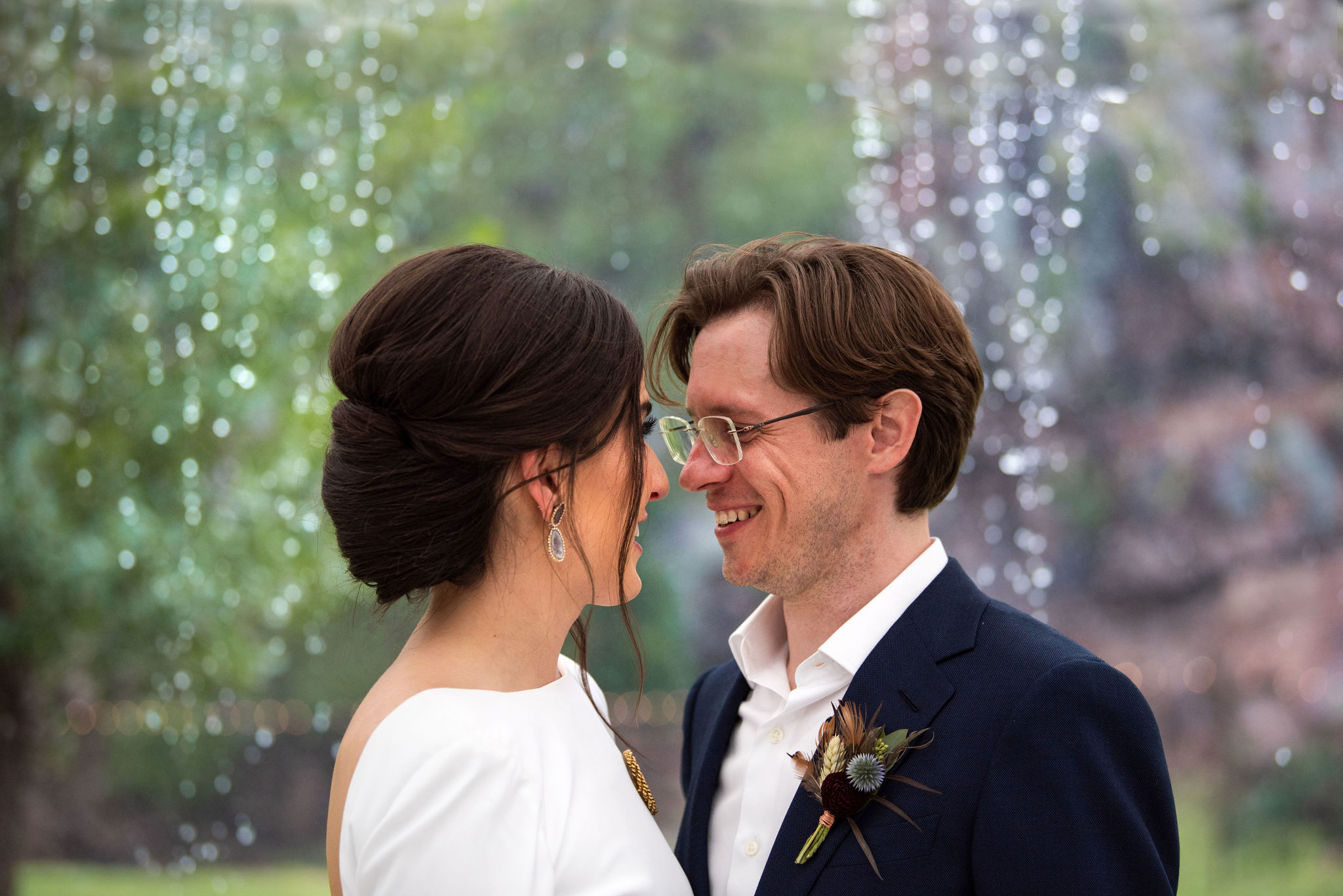 bride and groom stand and smile at each other during micro wedding at river bend venue in lyons colorado.