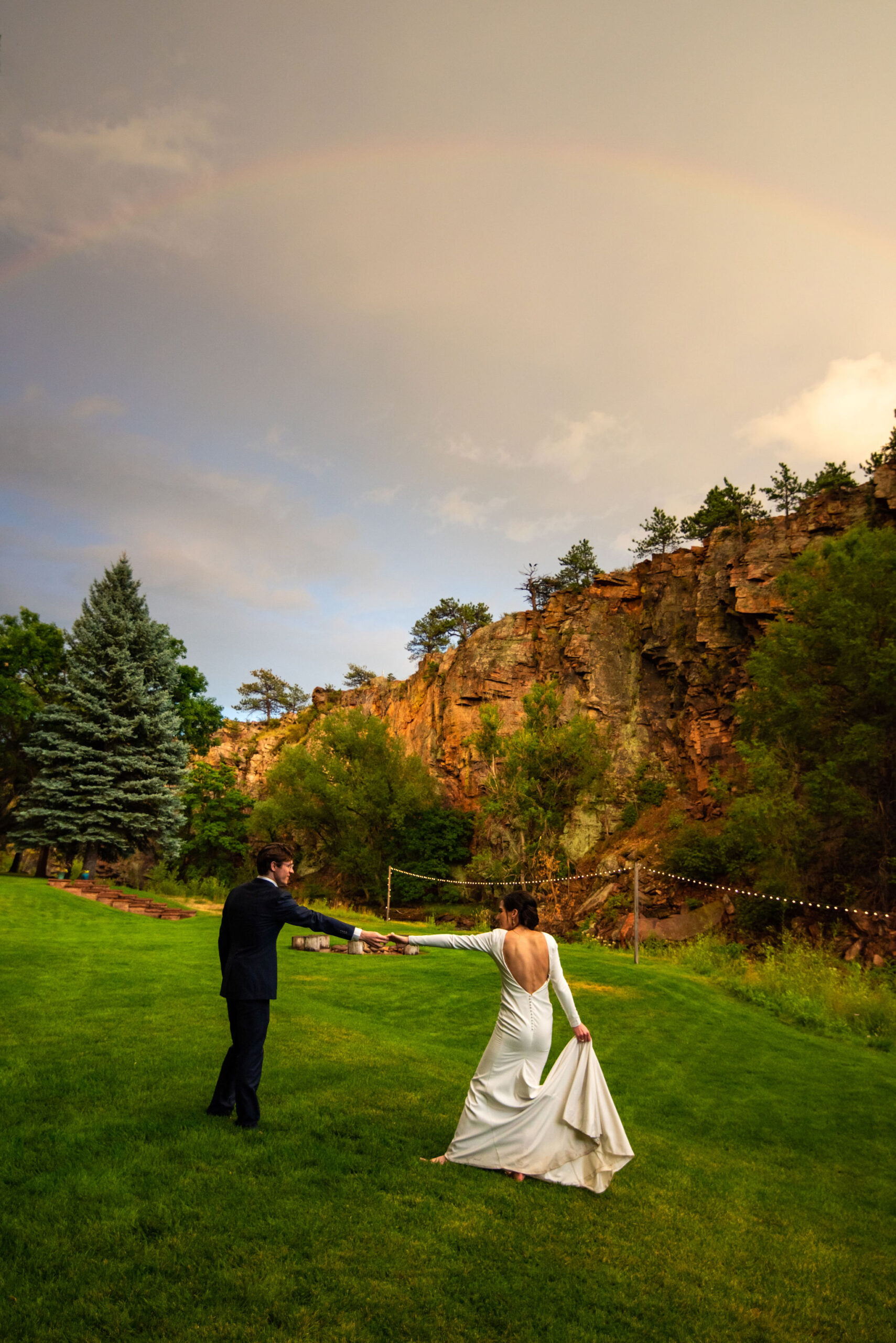 bride and groom dance under rainbow at river bend wedding venue during colorado micro wedding.