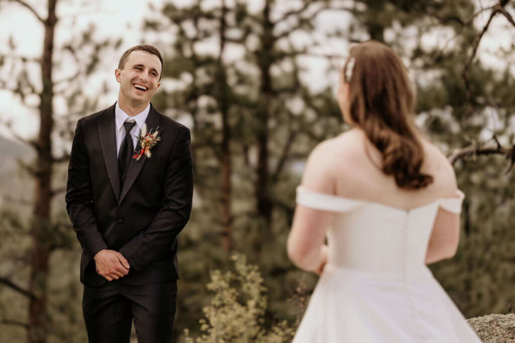 groom turns to look at bride for first look during colorado micro wedding in the mountains.
