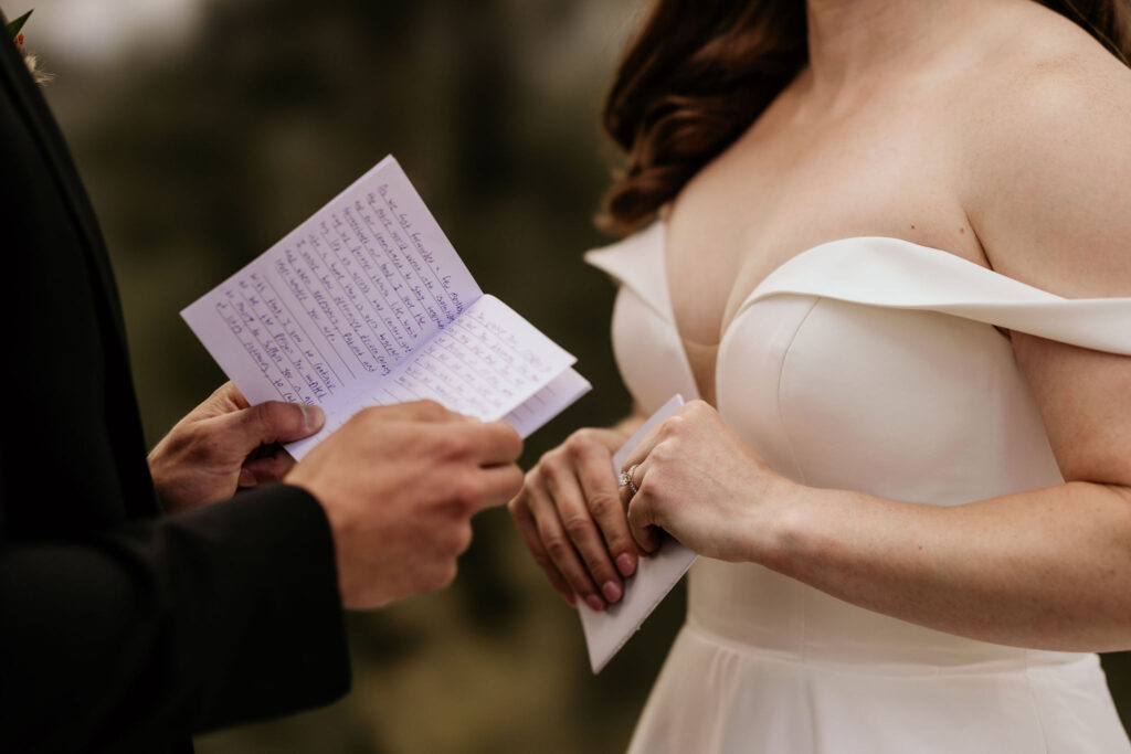 close up image of groom holding self written vows during colorado micro wedding.