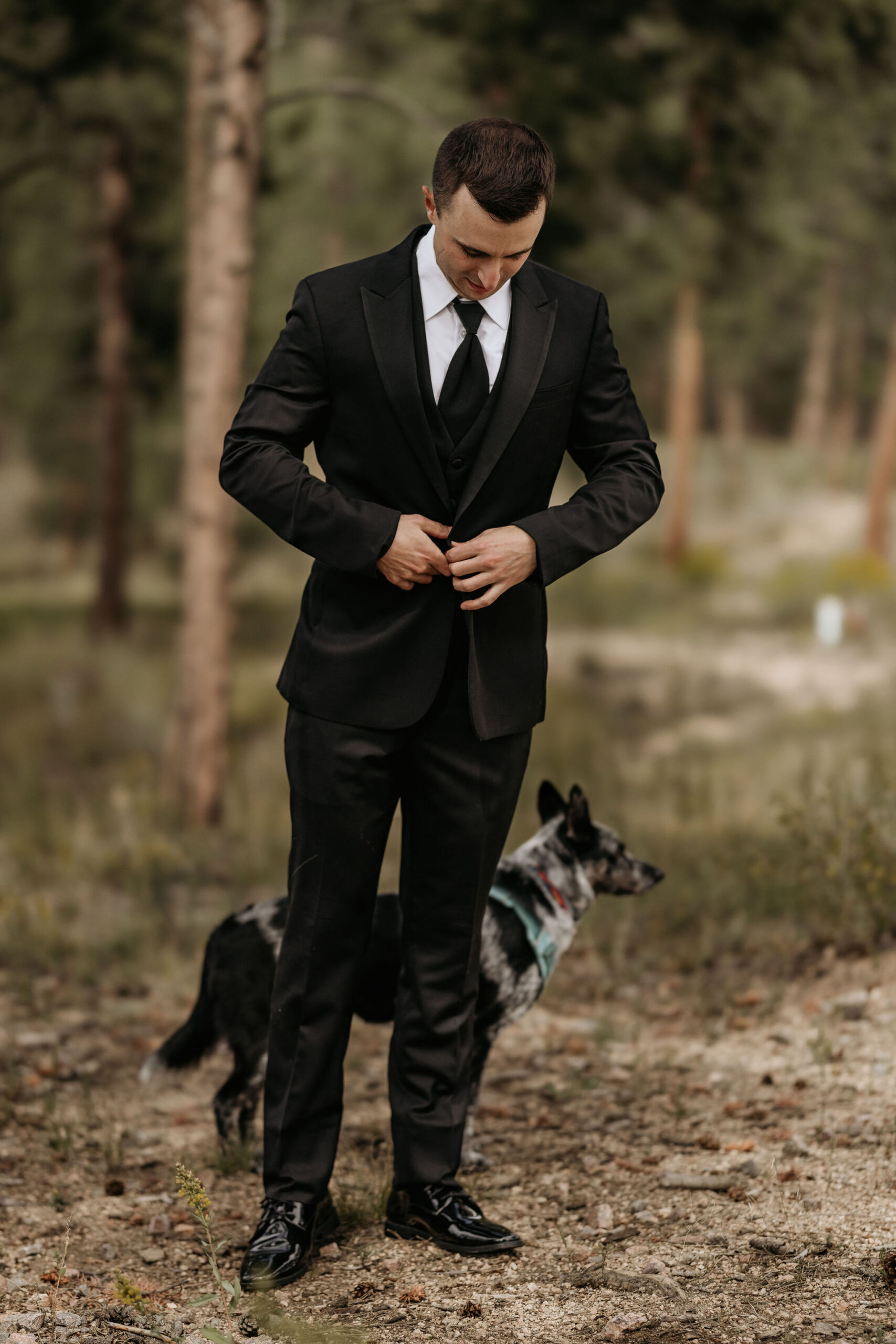 Groom and his dog stand outside during mountain top micro wedding in colorado.