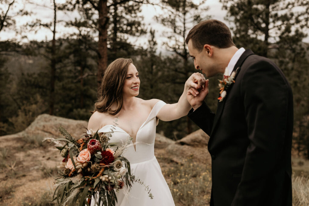 groom kisses brides hand during wedding portraits for their colorado micro wedding in the mountains.
