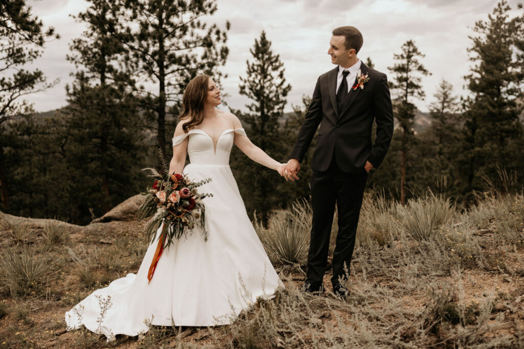 Bride and groom hold hands with the mountains in the background during colorado micro wedding.