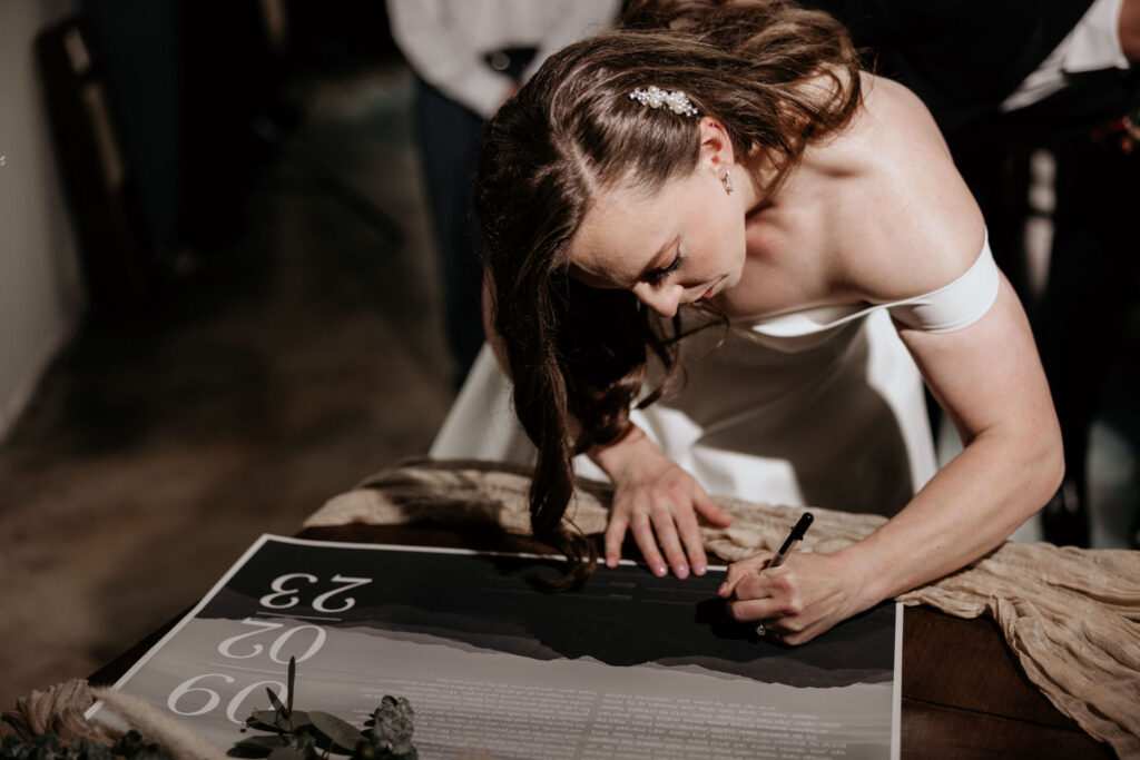 bride signs ketubah during colorado micro wedding.