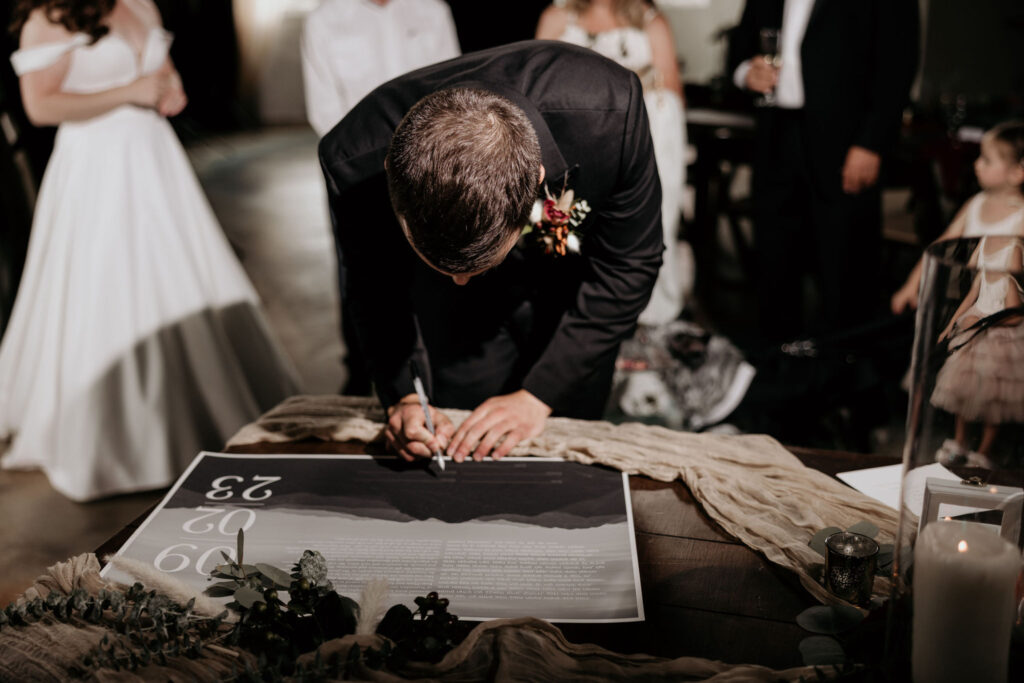 groom signs ketubah during colorado micro wedding.