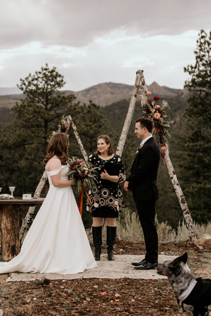 bride and groom stand in from of arch with mountains in the background during colorado micro wedding.