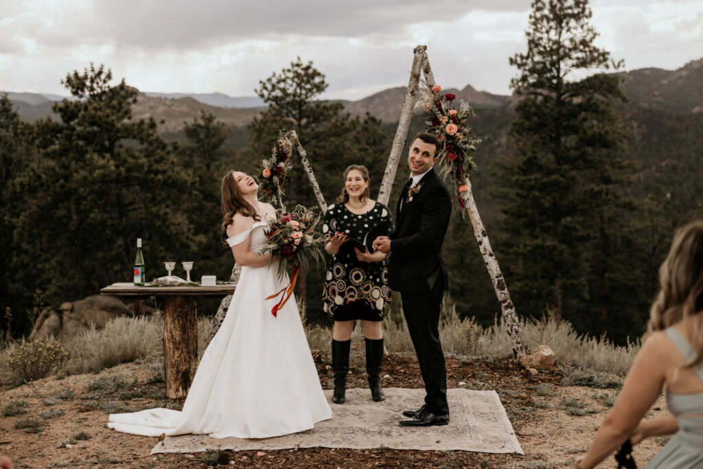 bride and groom laugh during micro wedding ceremony in the colorado mountains.