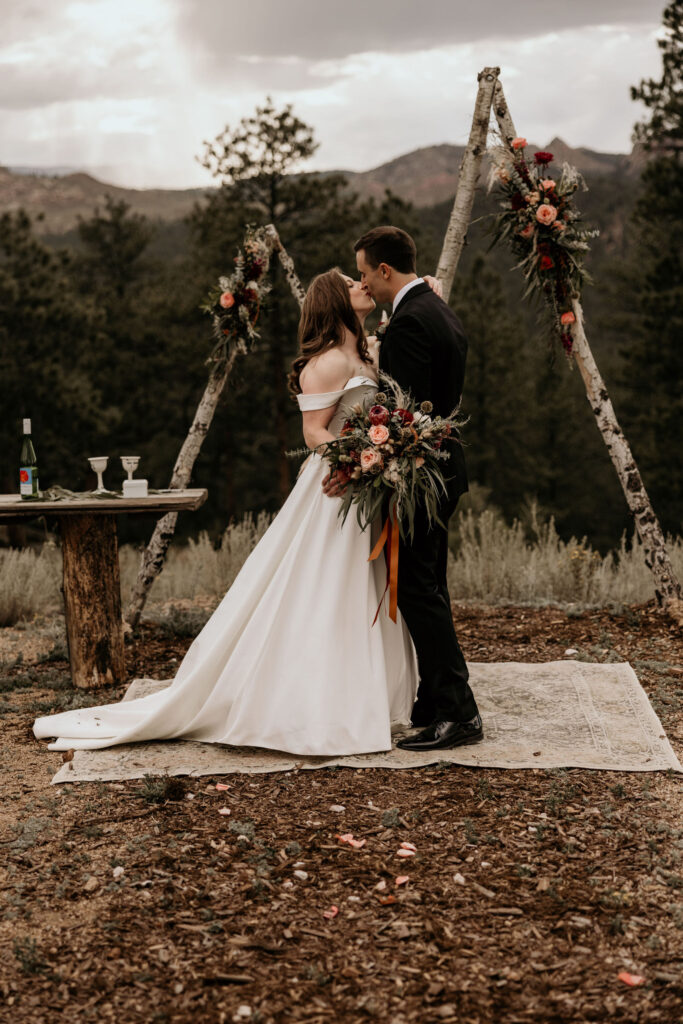 bride and groom kiss with the mountains in the background during colorado micro wedding.