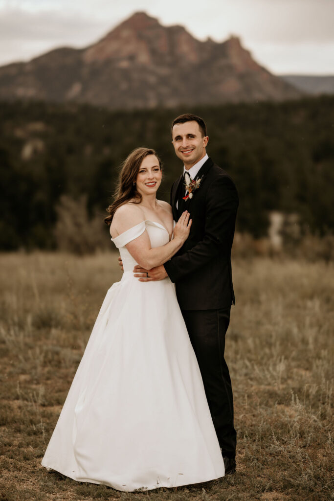 Bride and groom smile and pose with mountains in the background during colorado micro wedding.