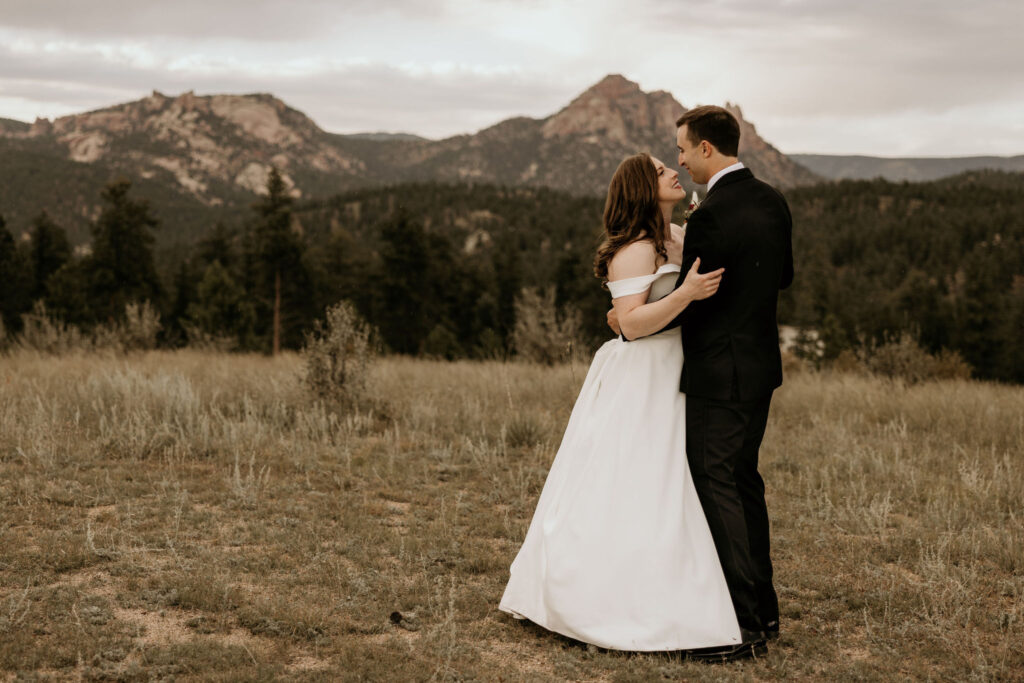 Bride and groom embrace with mountains in the background during colorado micro wedding.