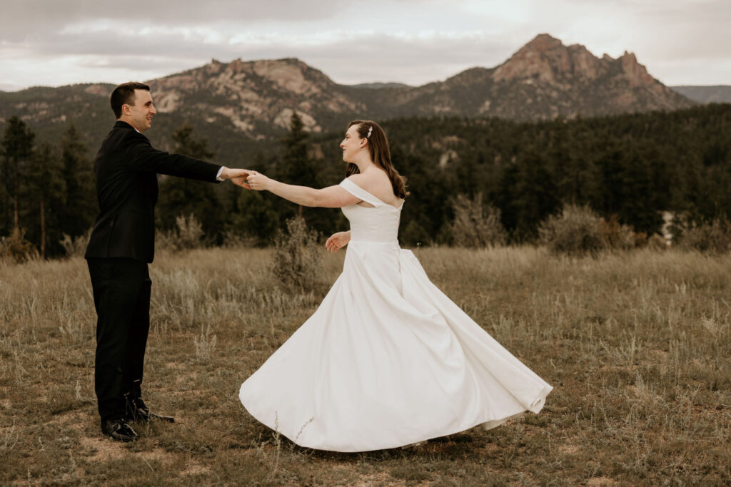 Bride and groom dance with mountains in the background during colorado micro wedding at Spires Ranch