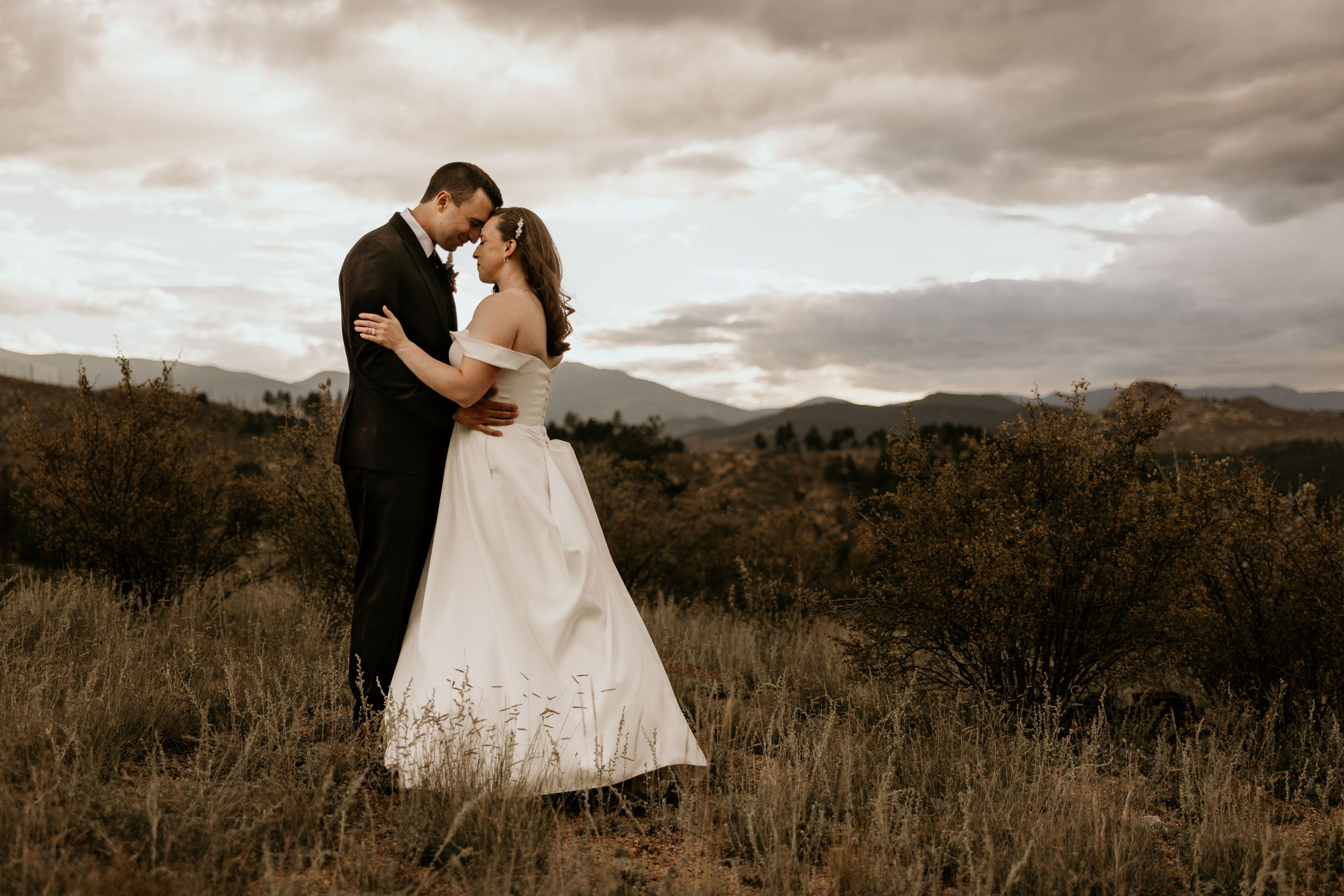 bride and groom press their heads together during sunset with the mountains in the background during their colorado micro wedding.