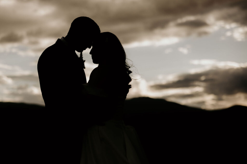 Shadow of bride and groom pressing their heads together during sunset with the mountains in the background during their colorado micro wedding.