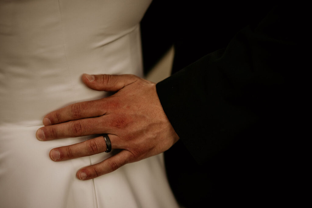 close up image of grooms hand on brides waist during mountain micro wedding in colorado.