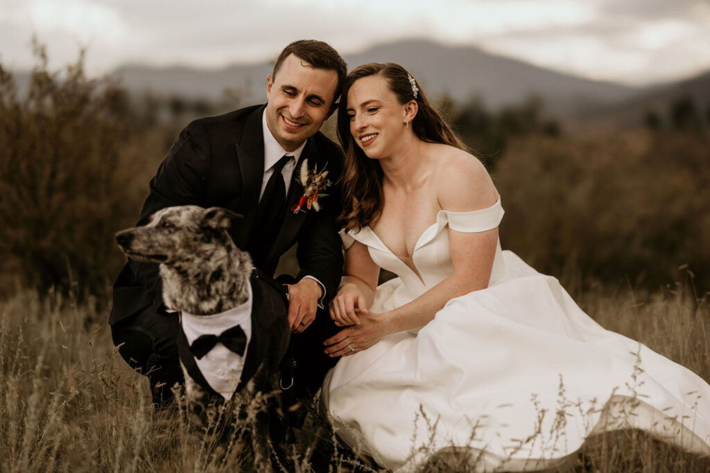 bride, groom, and dog in a tux smile during their mountain top micro wedding in colorado.