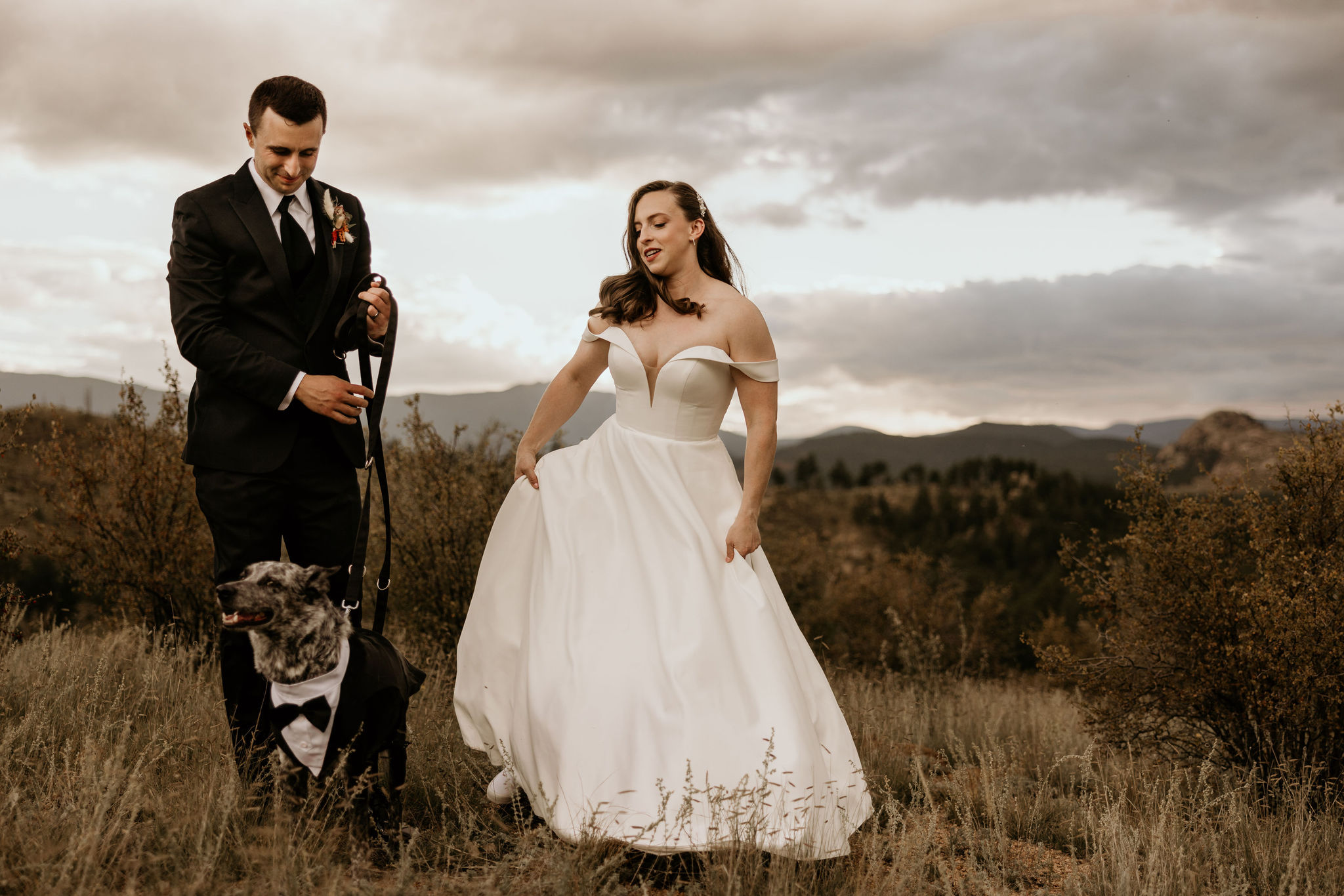 bride, groom, and pup walk along mountaintop during colorado micro wedding.