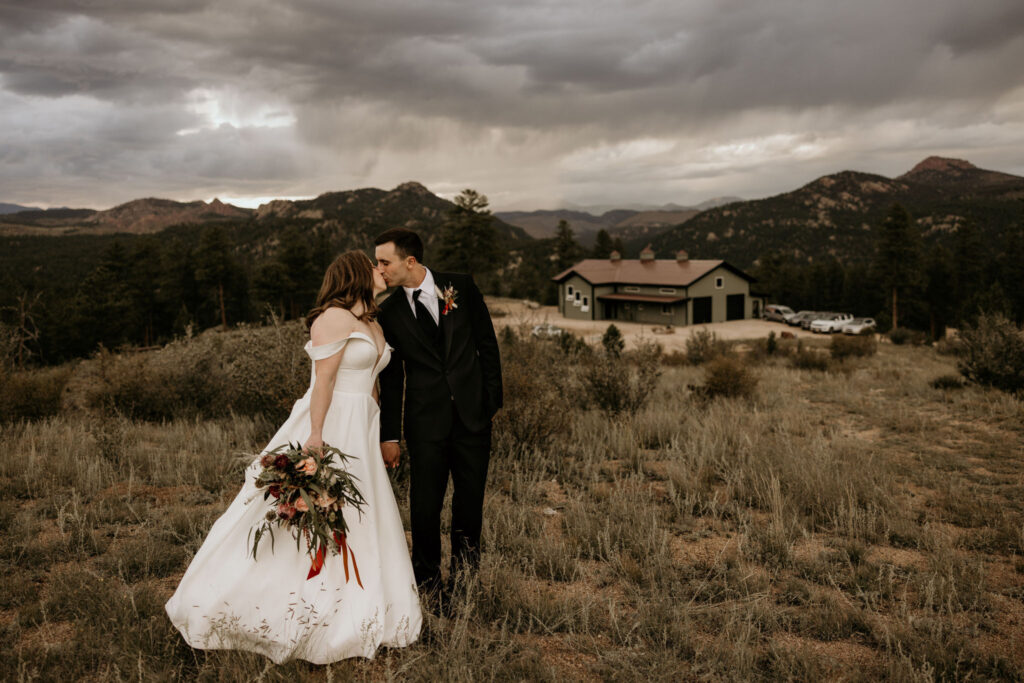 bride and groom kiss on mountain top during colorado micro wedding.