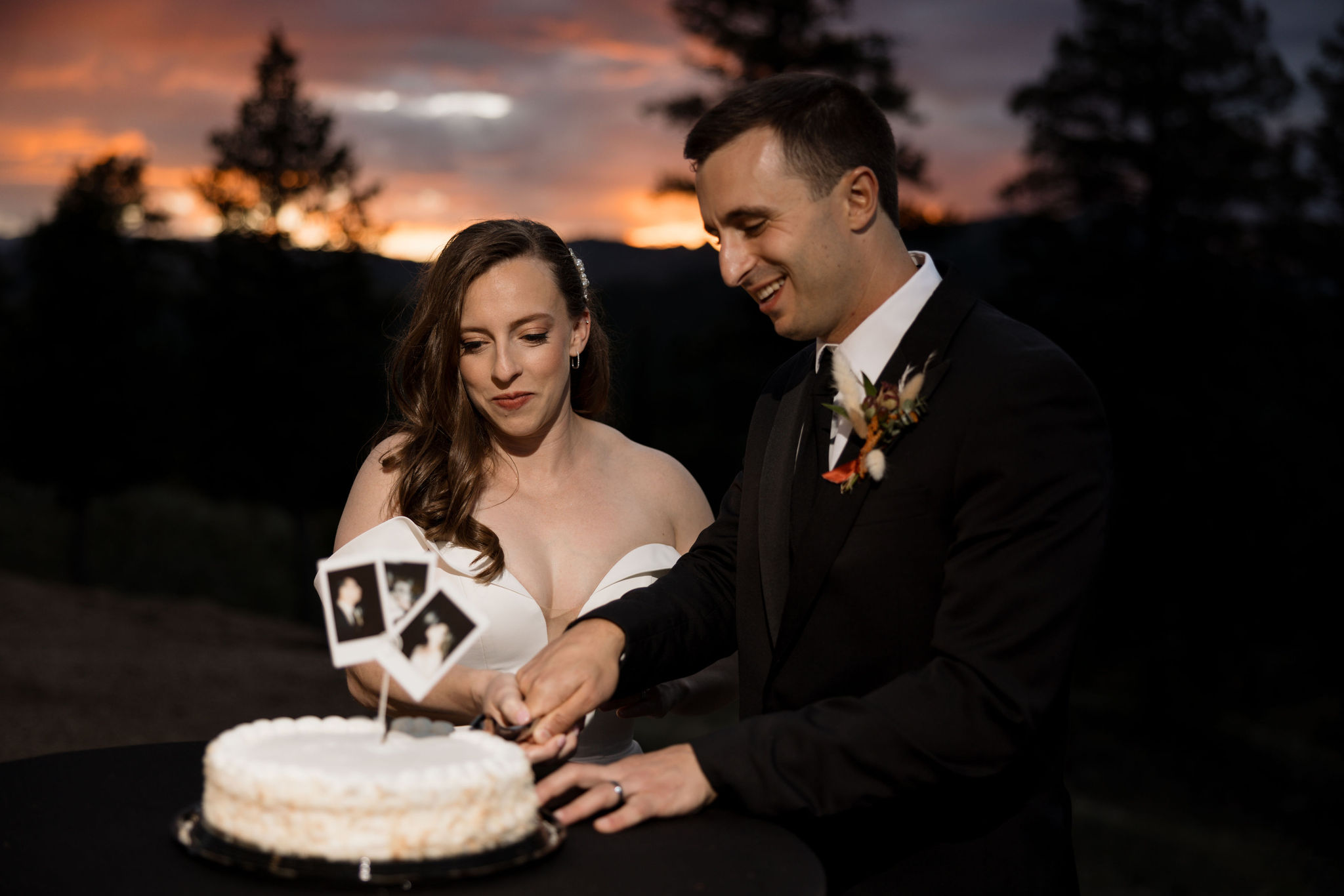 bride and groom cut cake in front of the sunset during their mountain top micro wedding in colorado.