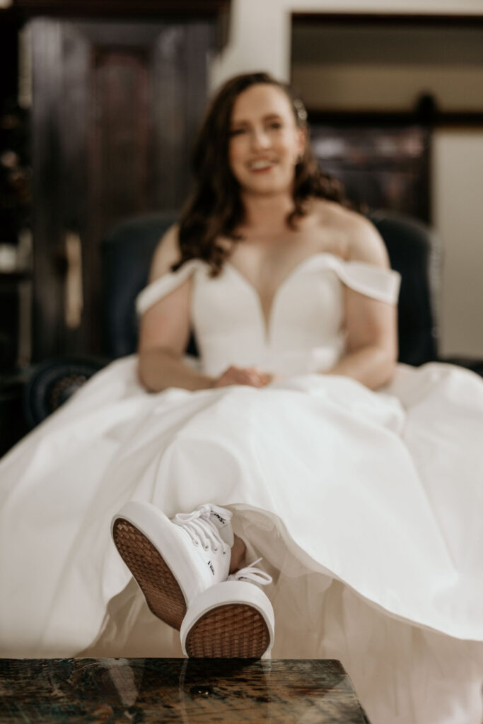 bride sits with feet up in sneakers during mountain micro wedding in colorado.