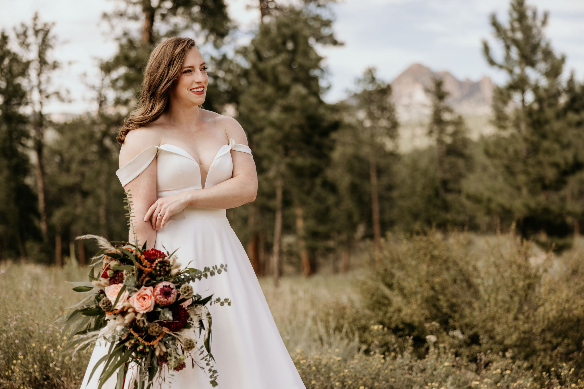 bride holds bouquet outside with the mountains in the background during colorado micro wedding.