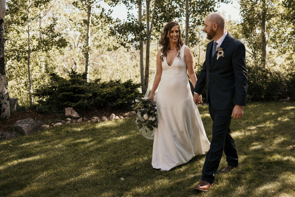 Bride and groom hold hands and walk during summer colorado mountain micro wedding.