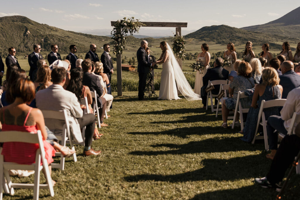 bride and groom stand up front at their colorado mountain wedding ceremony in the summer.