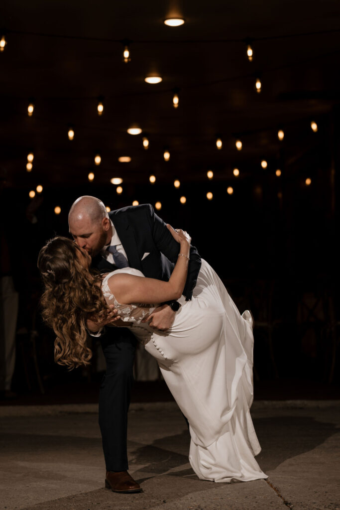 groom dips bride and kisses her on the dancefloor during summer wedding reception in colorado.