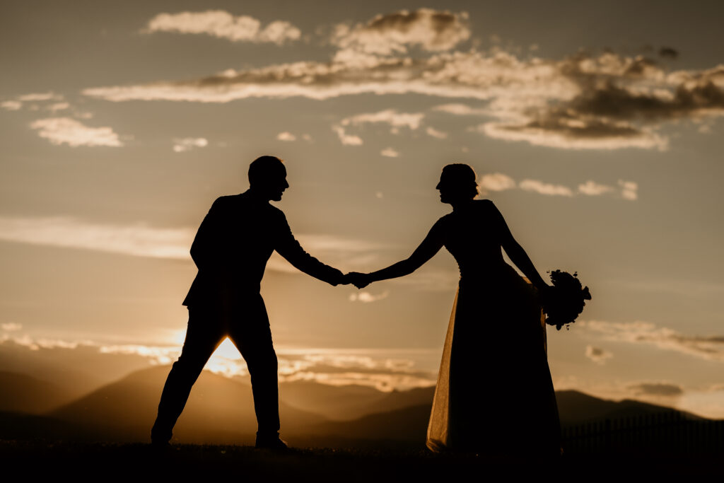 Shadow of bride and groom holding hands with the sunset and colorado mountains in the background, during spring wedding.
