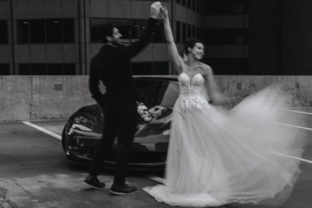 Black and white image of groom twirling bride during bridal portrait photos.