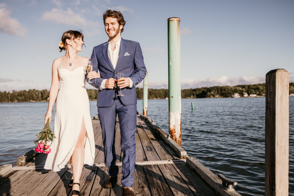 Bride and groom walk arm in arm down the dock during their lake micro wedding in colorado.