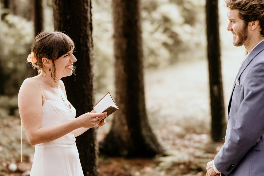 Bride reads seld-written vows in the middle of the forest during a summer mountain micro wedding in colorado.