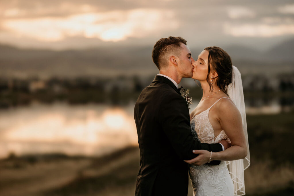 Bride and groom kiss in front of the colorado sunset during spring micro wedding.